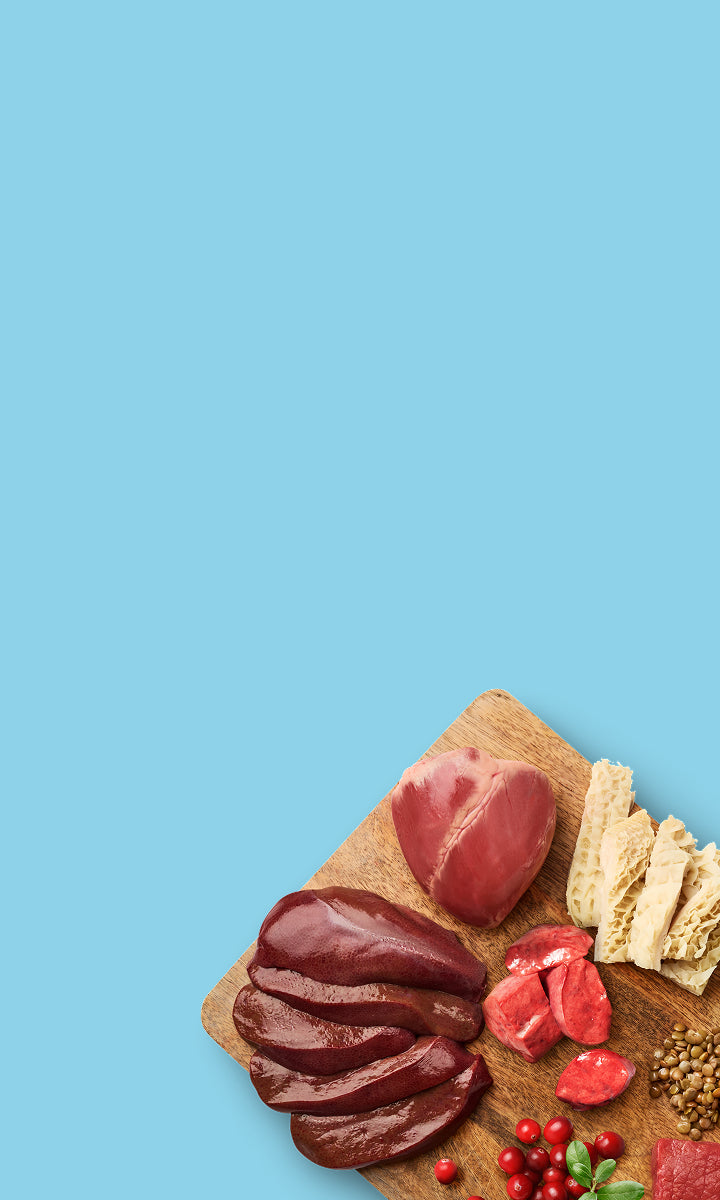 Wooden cutting board with sliced meats and berries on a blue background