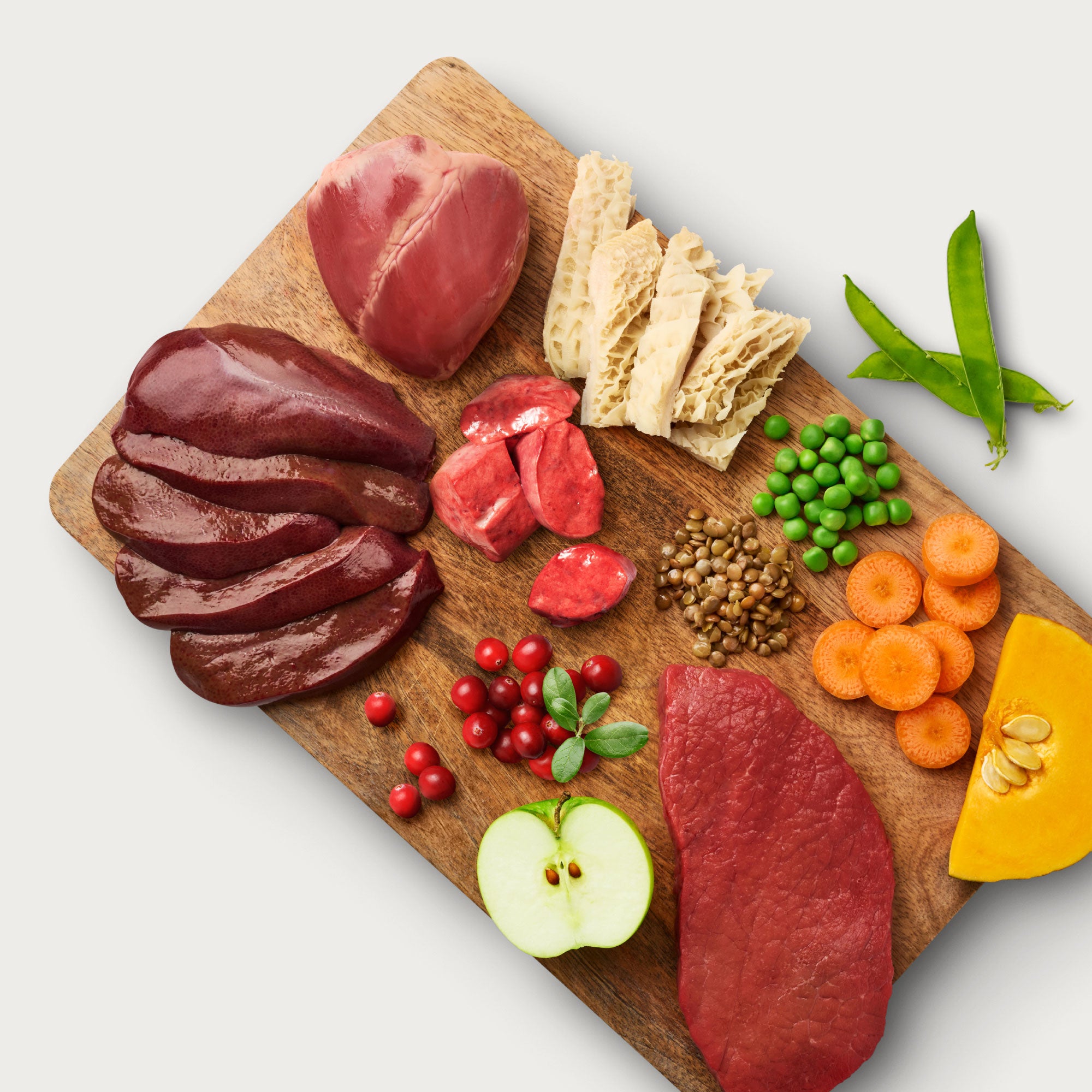 Assorted meats, vegetables, and bread on a wooden cutting board.